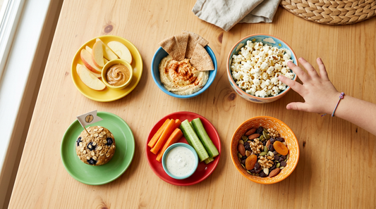High-fiber after-school snacks for kids including apple slices popcorn and trail mix on kitchen counter