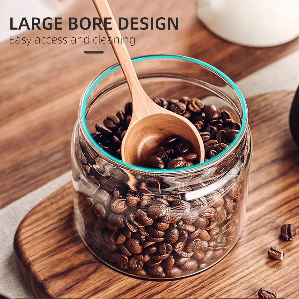 Glass jar with coffee beans and a wooden spoon on a wooden surface, with text about large bore design.
